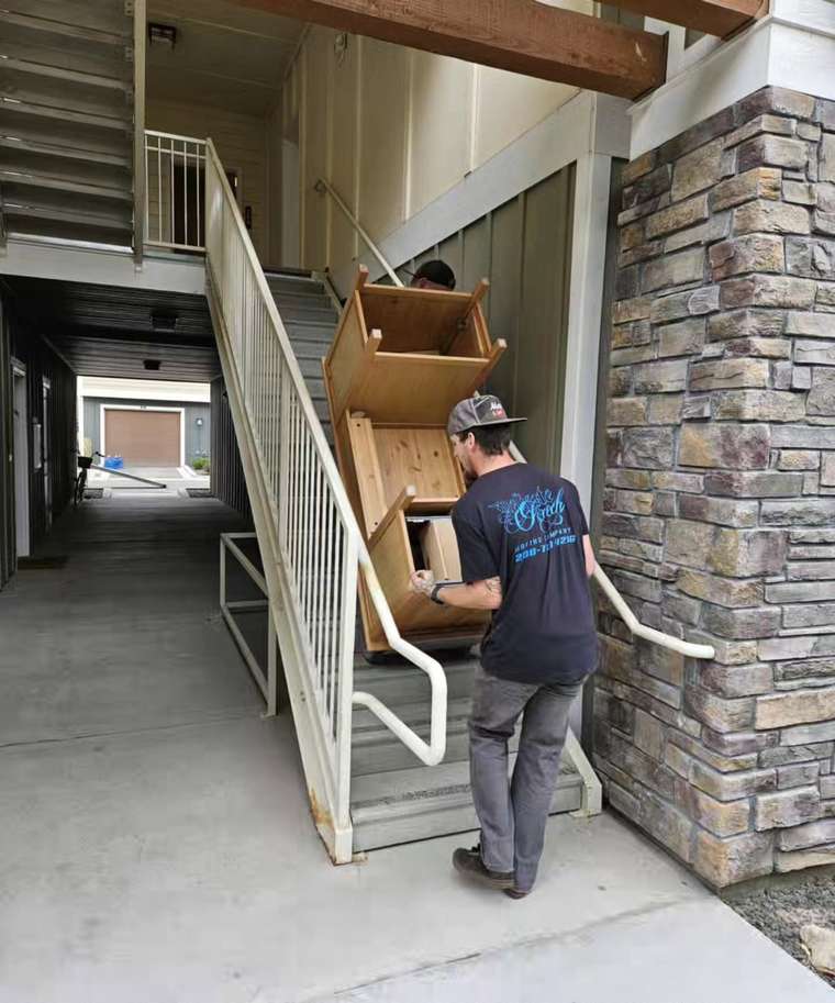 Movers carrying boxes through an apartment building corridor