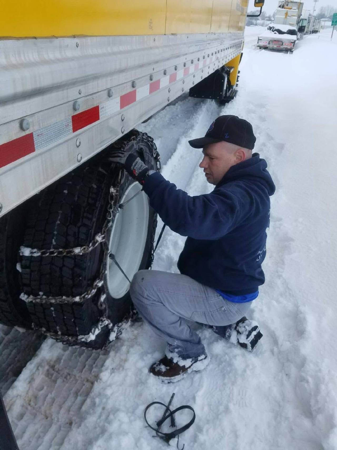 Tim fitting tire chains to a rented Penske trailer during a winter long-distance move