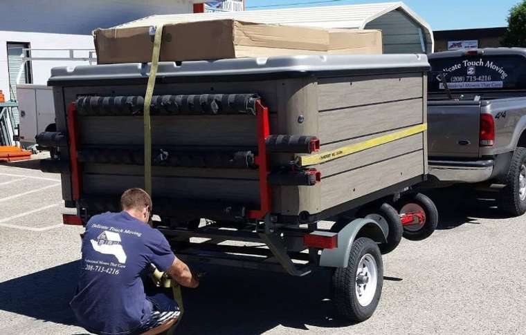 Crew moving a hot tub on its side across a yard