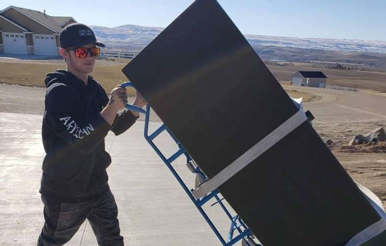 Movers strapping a gun safe to a heavy-duty dolly